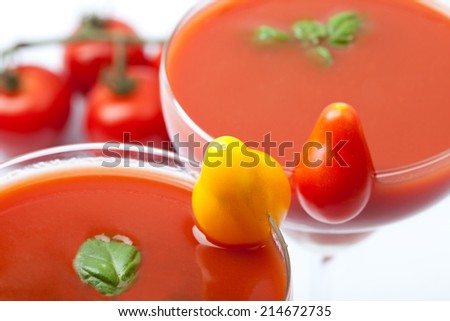 tomato juice with cocktail tomatoes and fresh basil inside cocktail glass, white background, isolated, aerial view, landscape format
