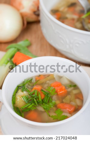 vegetable soup in white bowl, big soup bowl in background, vegetables around, aerial view, portrait format