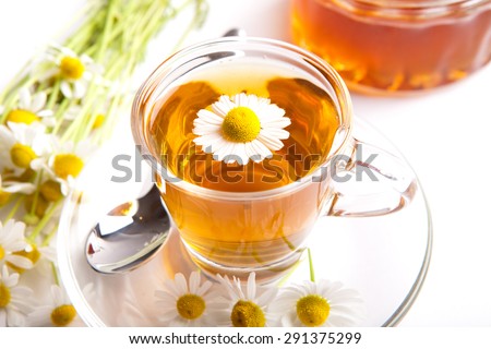 herbal chamomile tea on white background, with blooming plants, blossom inside teacup and honey