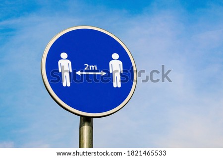 Keep two metres away. Safety distace icon on blue circular sign on the background of blue sky. Coronavirus epidemic social advice. 2 m rule. Stok fotoğraf © 