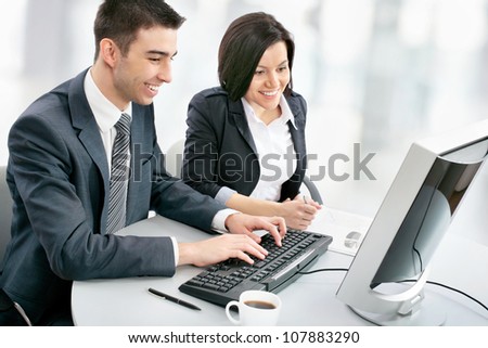Smiling business people with computer in board room