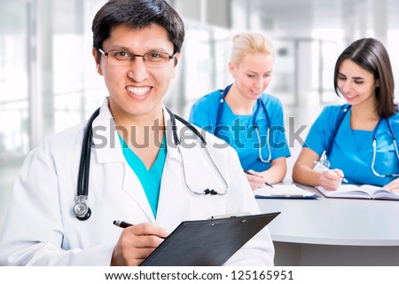 Portrait of a smart male doctor sitting in front of his team and smiling
