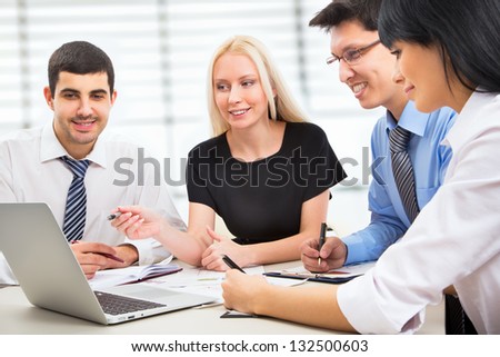 A business team of four plan work in office