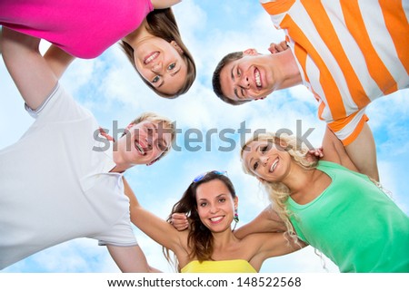 Group of happy young people in circle at beach have fun and smile
