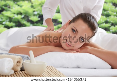 Beautiful young woman lying relaxed in a spa salon and receiving facial massage. Beauty treatment.