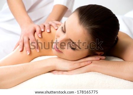 Masseur doing massage on the back of woman in the spa salon. Beauty treatment concept.