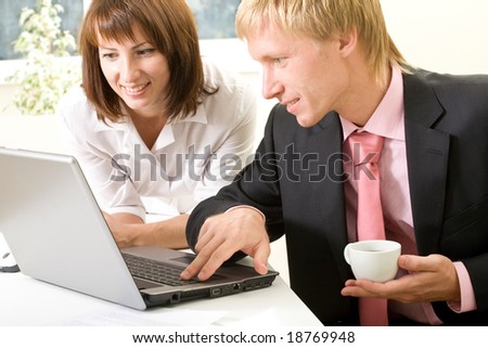 Image of successful businessman touching key of laptop with pretty female near by