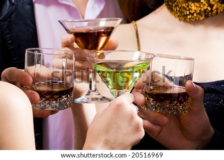 Four human hands holding the glasses of cocktails making a toast