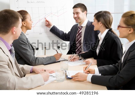Image of smart business people looking at their leader while he explaining something on whiteboard during seminar