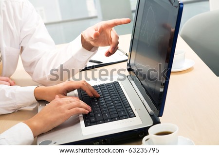 Close-up business man hand showing something on laptop to his colleague