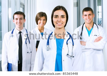 Young doctors are standing inside the hospital and looking at camera