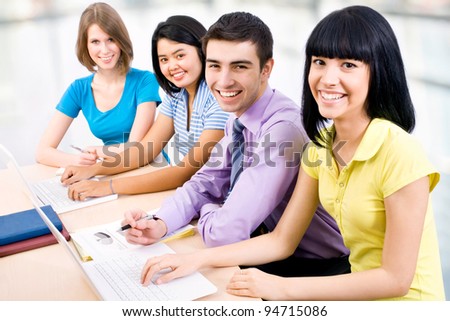 Happy group of young students studying together in a college