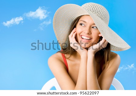 Beautiful woman with hat smiling on a background of blue sky