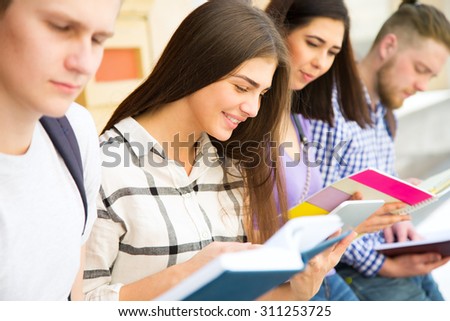 Group of university students studying, reviewing homework in park