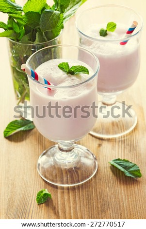 Two glasses with milk cocktail decorated with mint leaves. Vintage toning