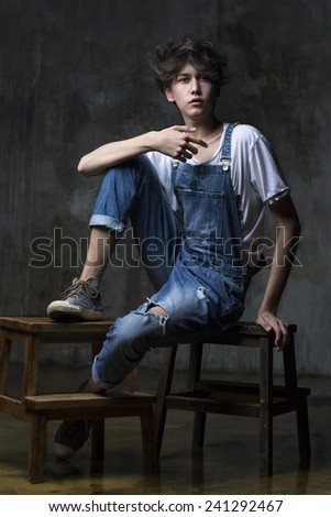 Young handsome man in jeans sitting on a small stool