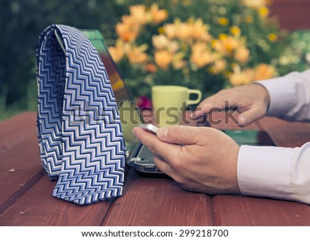 Freelance or remote work concept. Focus on smartphone in male\'s hand.