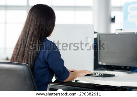 Rear view of businesswoman using desktop computer in office
