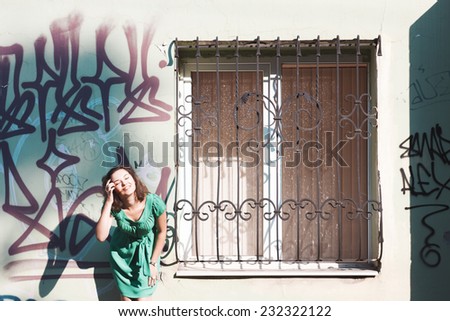 Street portrait of smiling girl. Beautiful brunette in green dress. Graffiti on wall