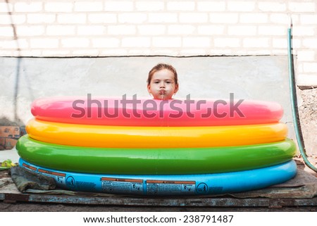 Girl swimming in pool. Girl\'s head on edge of inflatable pool. Funny moment. Colors of rainbow