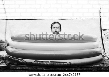 Girl in pool. Girl\'s head on rim of inflatable pools. Funny portrait of child. Black and white photo