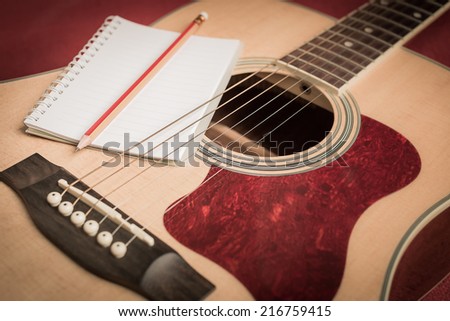 Notebook and pencil on guitar for writing music