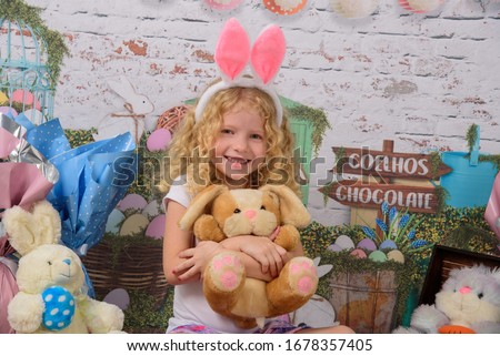 Cuty little girl in the ears of the Easter bunny holds a rabbit a sausage, with Easter background scenery. The child smiles Foto stock © 