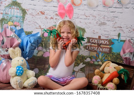 Cuty little girl in the ears of the Easter bunny holds a rabbit a sausage, with Easter background scenery. The child smiles Foto stock © 