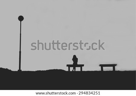 The silhouette of woman sitting alone with grey sky, concept of lonely, sad, alone, person space