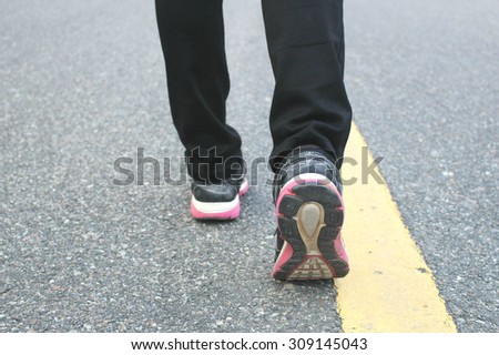 The close up shot of walking shoes on the road, selected focus on the right shoe