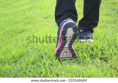 The close up shot of walking shoes on the green grass, selected focus on the left shoe