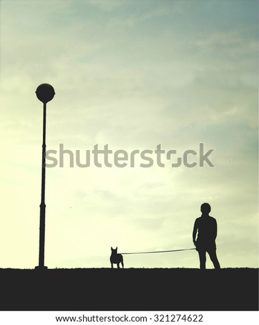 The silhouette lonely human and his dog with the early evening sky, concept of man best friend. Selective focus with the silhouette