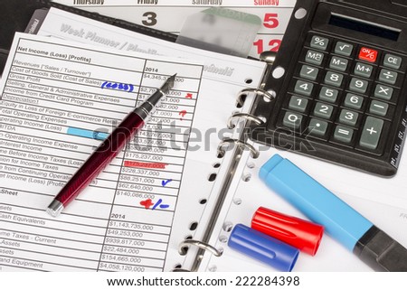 Week planner, pen, calculator, colored markers and sheets of financial statements