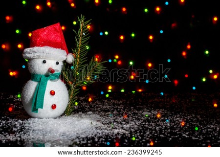 Christmas decoration - snow man with fir branch on black background with colored lights