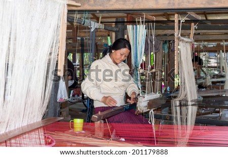 LUANG PRABANG, LAOS - 8 DEC, 2013: Unidentified female worker in silk production factory. Traditional way of making textile is very popular tourist attraction.