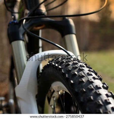 Front wheel of a mountain bike close up and behind the suspension fork.