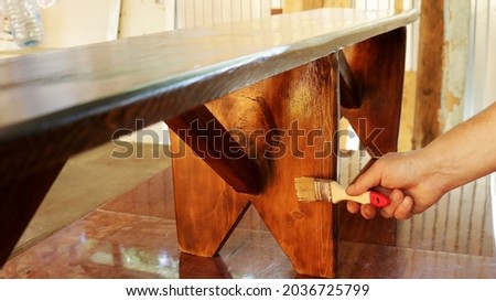 applying varnish on a wooden bench in a workshop, varnishing a wooden product by hand, manual lacquering of handmade furniture, processing with a protective varnish a bench made of wood Foto stock © 