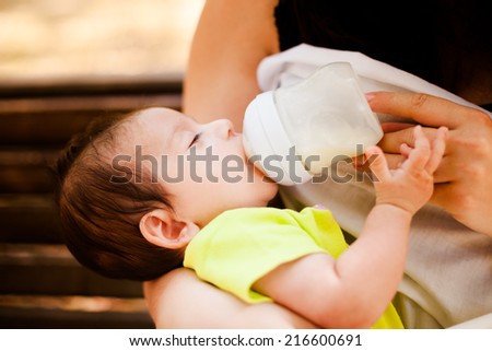 The image of the woman feeding her newborn baby from a children\'s small bottle