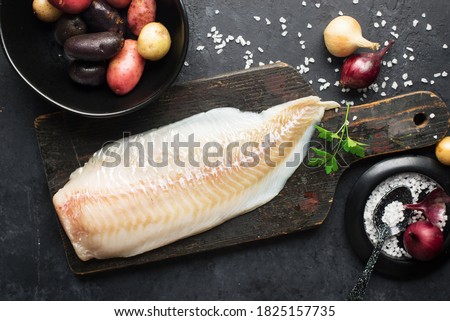 Cod white fish potatoes dish ingredients for healthy comfortable home food. Raw white fish fillet in a baking dish on a dark background. Top view. Stockfoto © 