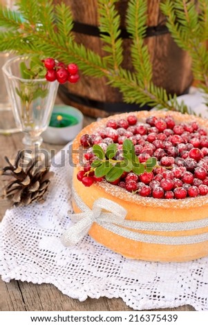homemade cake with cranberries on a white tablecloth with candles and wine glasses