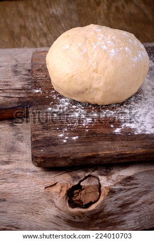 Small balls of fresh homemade dough on floured wooden board  Selective Focus, Focus one third into the first dough