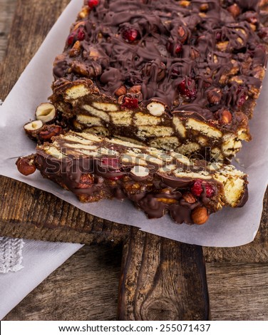 Mosaic Chocolate and Biscuit Cake with hazelnuts and cherries on a wooden background
