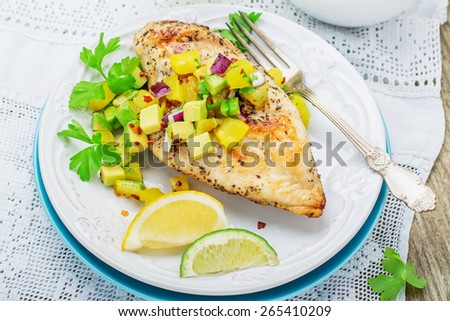 Grilled chicken breast with salsa pineapple, avocado and sweet red onion, parsley and cilantro. Posted on a white plate on the table with a white lace vintage tablecloth. selective Focus