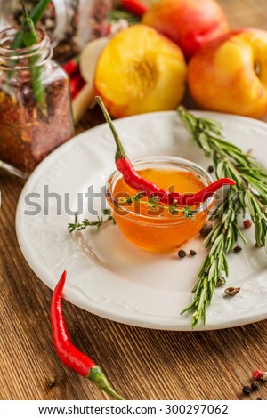 Home hot sauce made with peaches and hot pepper to the meat in portion bowl with herbs, pepper and garlic on ceramic plate on a wooden background. yborochny focus. concept of healthy homemade food