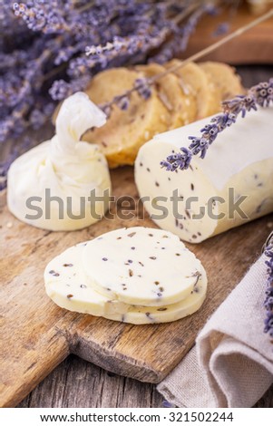 Fresh homemade butter with lavender flowers in a rolled parchment on a wooden cutting board with lavender flowers. The concept of natural organic food home. selective Focus