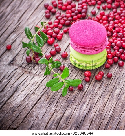 Bright macaroon cake with cranberries and pistachios on a background of ripe berries on the texture wooden background. selective Focus