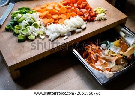 Ready-cut raw vegetables, prepare for cooking on a wooden board and next to it in a silver bowl the organic compost. Photo stock © 