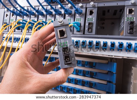 man working in network server room with fiber optic hub for digital communications and internet