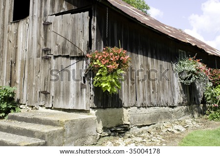 Old worn down barn with hanging flower ports and beautiful flowers.
