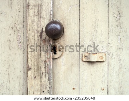 Old lock with a round door knob on a weathered, beige wooden gate
